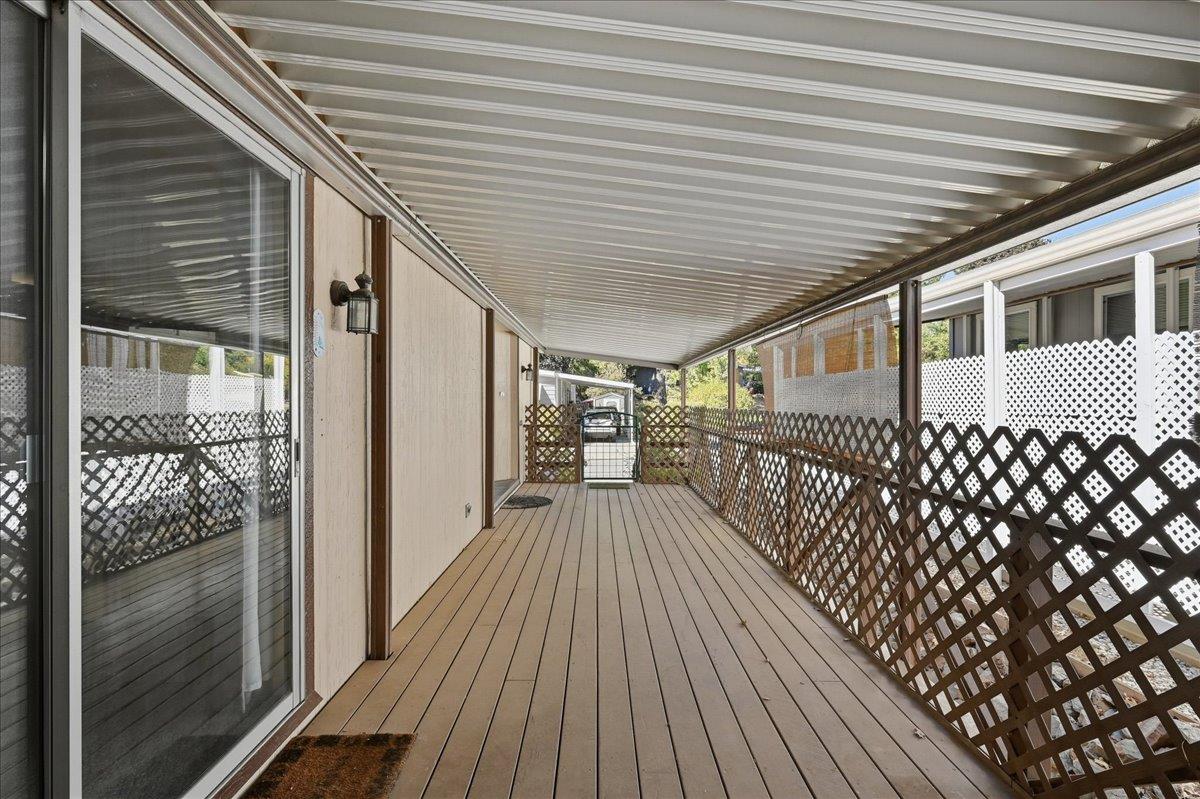 Covered deck with brown plank flooring, lattice railings, and a sliding glass door.