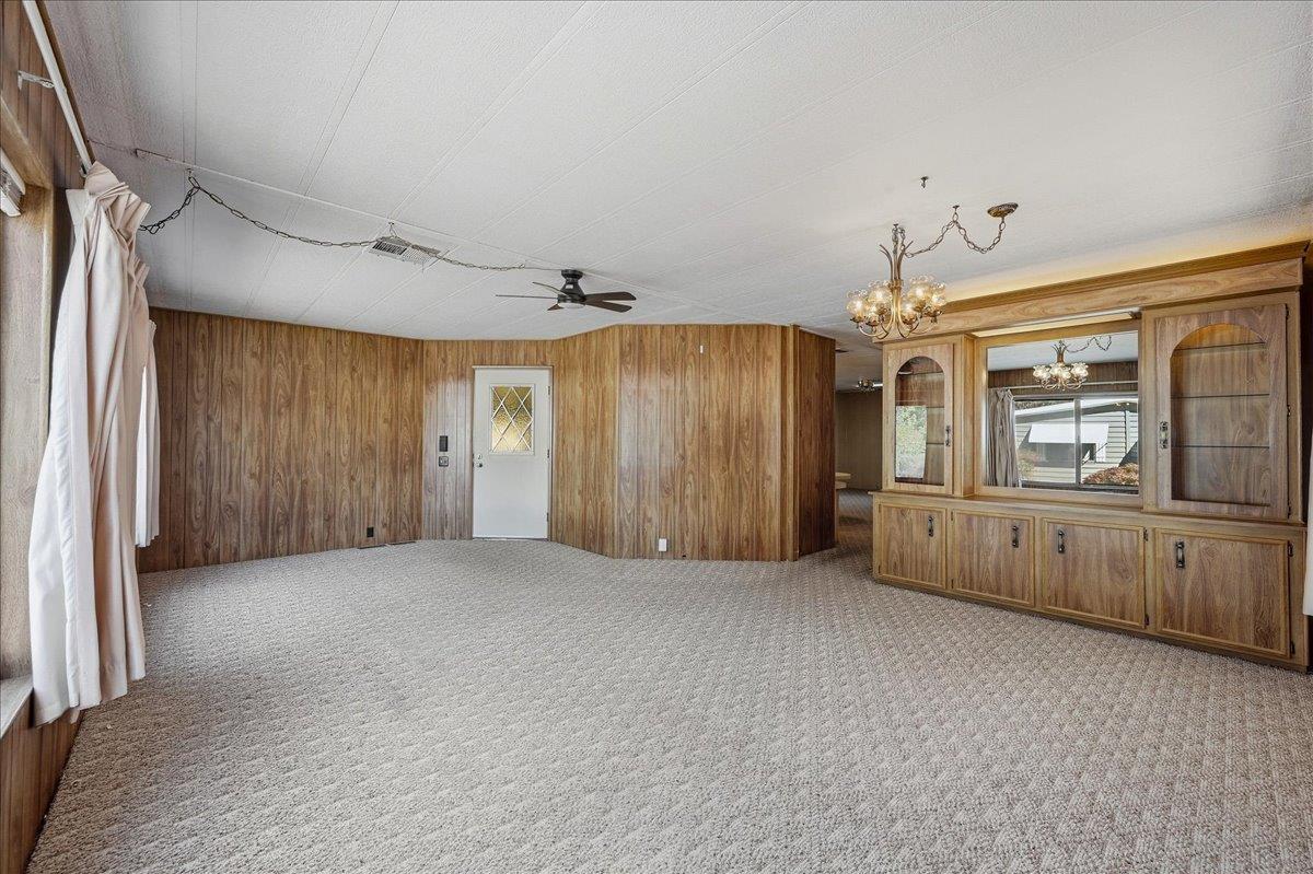 Vacant living room with wood paneling, built-in cabinetry, and a carpeted floor.