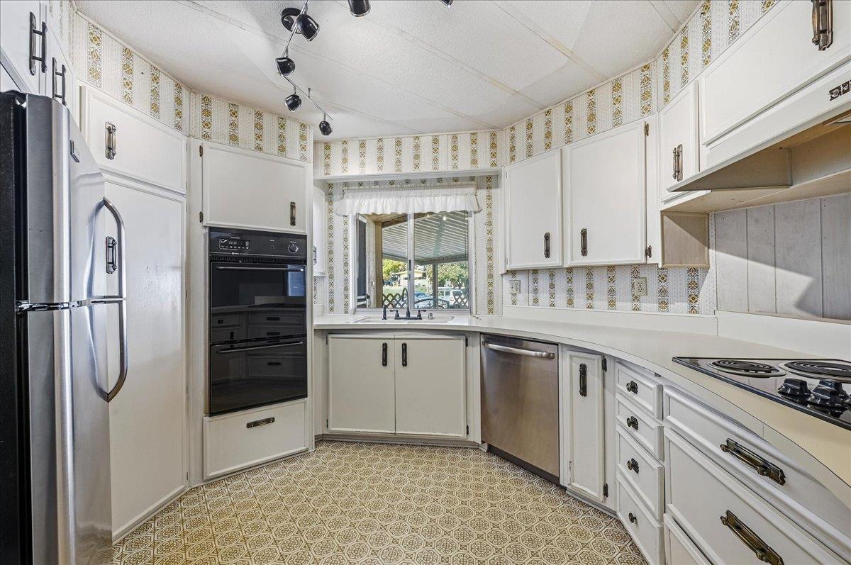 Kitchen with white cabinets, stainless appliances, and patterned tile flooring.