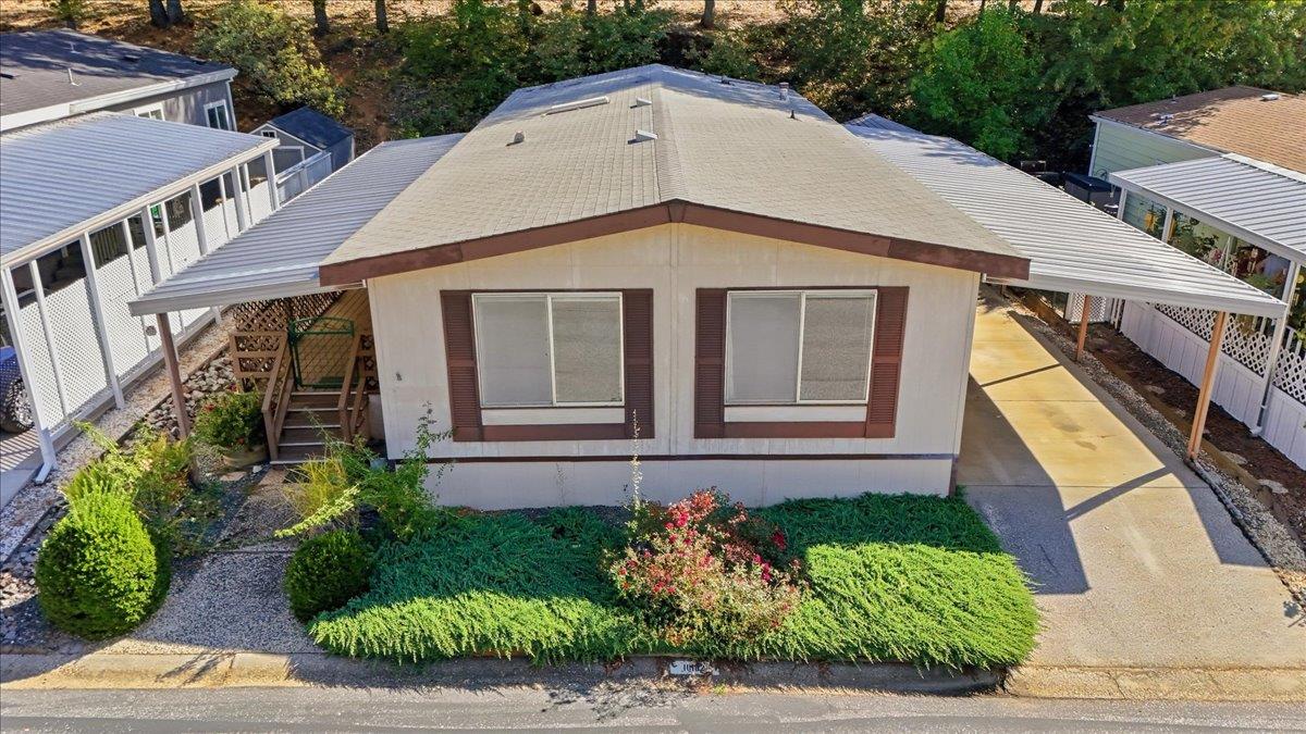 Single-story home with covered carports on both sides and flowering shrubs along the front.