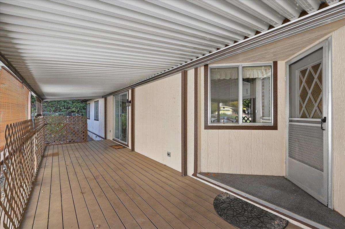 Covered deck with wood-plank flooring and lattice railing beside the house.