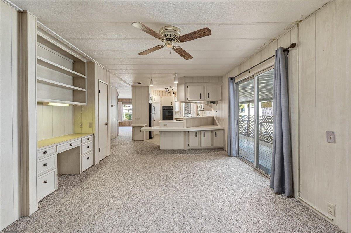Vacant kitchen and dining area with a breakfast bar, built-in desk, and sliding doors to a deck.