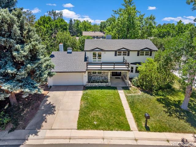 Two-story home with an attached garage, stone entry, and mature trees.