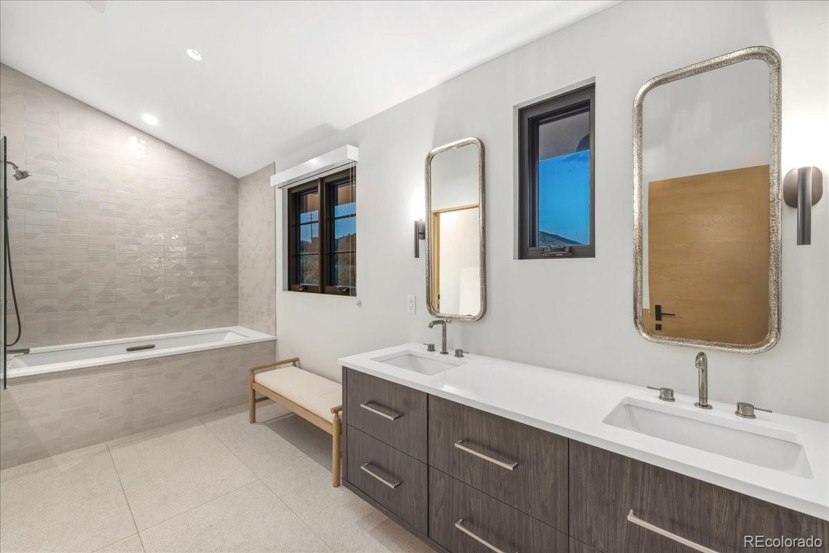 Bathroom with dual vanity, freestanding tub, and mountain view
