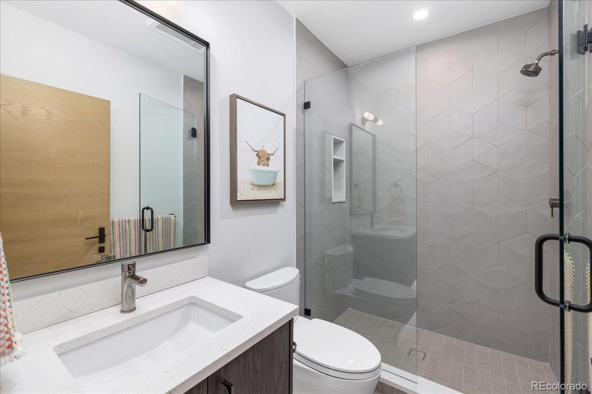 Bathroom with glass shower and gold-framed mirror