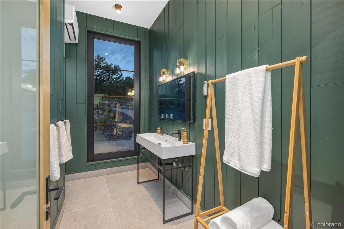 Bathroom with green accent wall and ladder towel rack