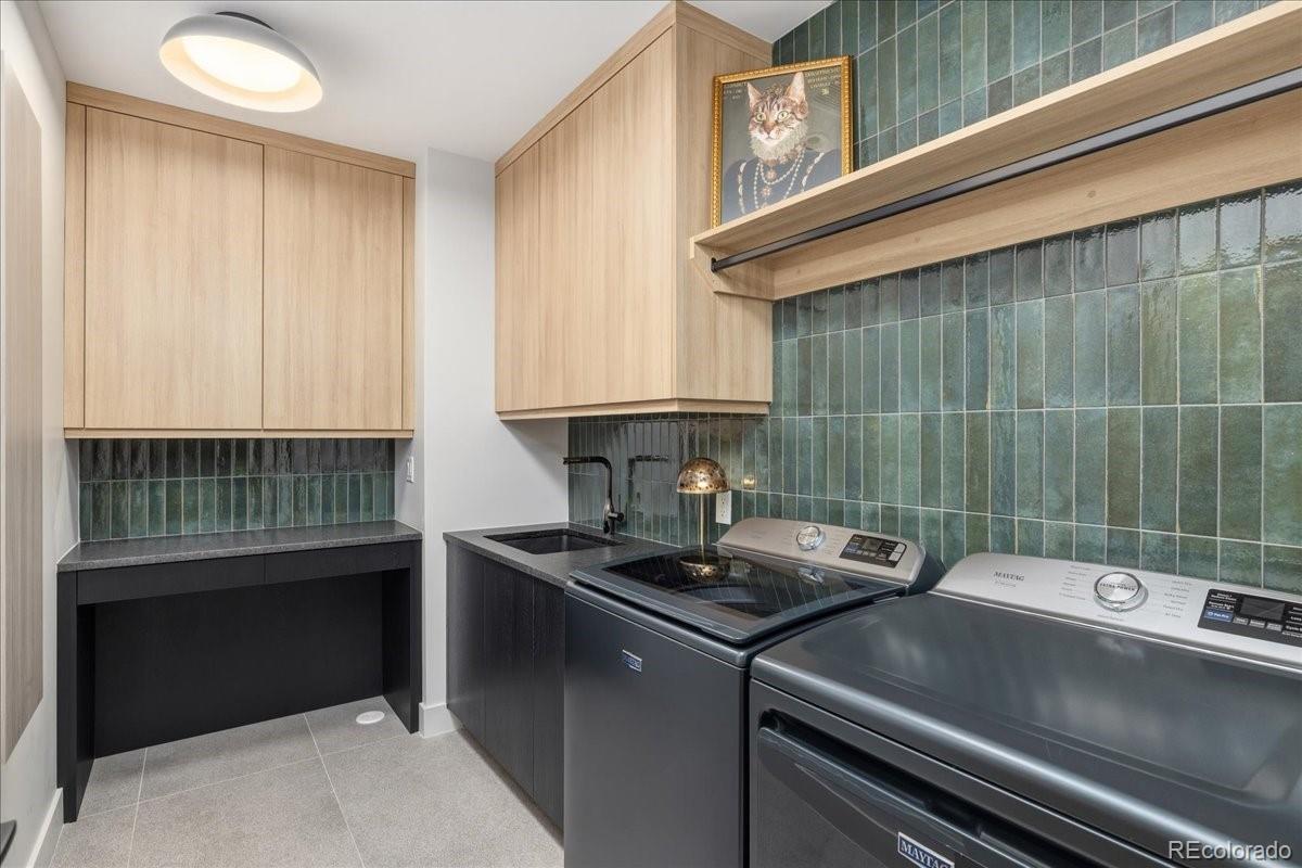 Laundry room with black appliances and green tile backsplash