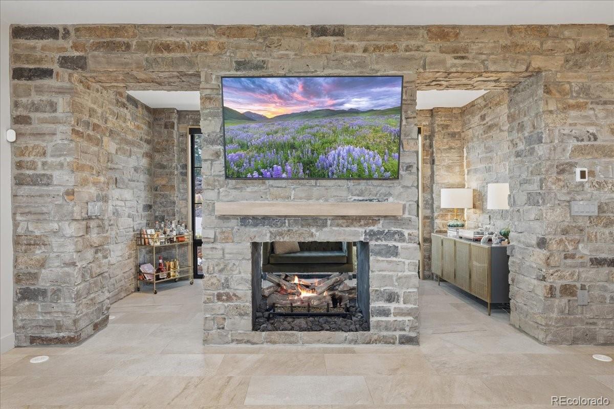 Stone fireplace wall with mounted TV and custom built-in cabinetry