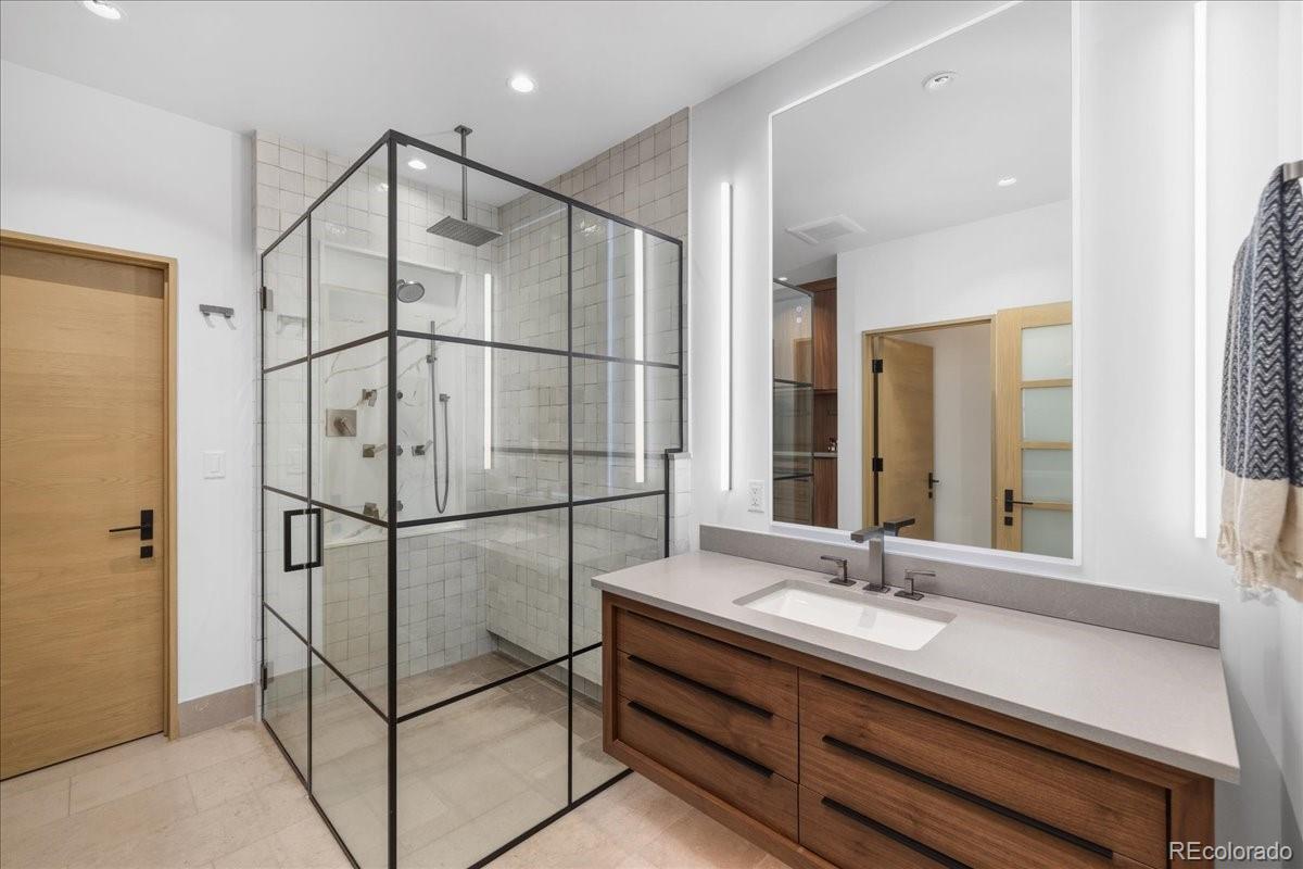 Bathroom with glass-enclosed shower and dual vanity