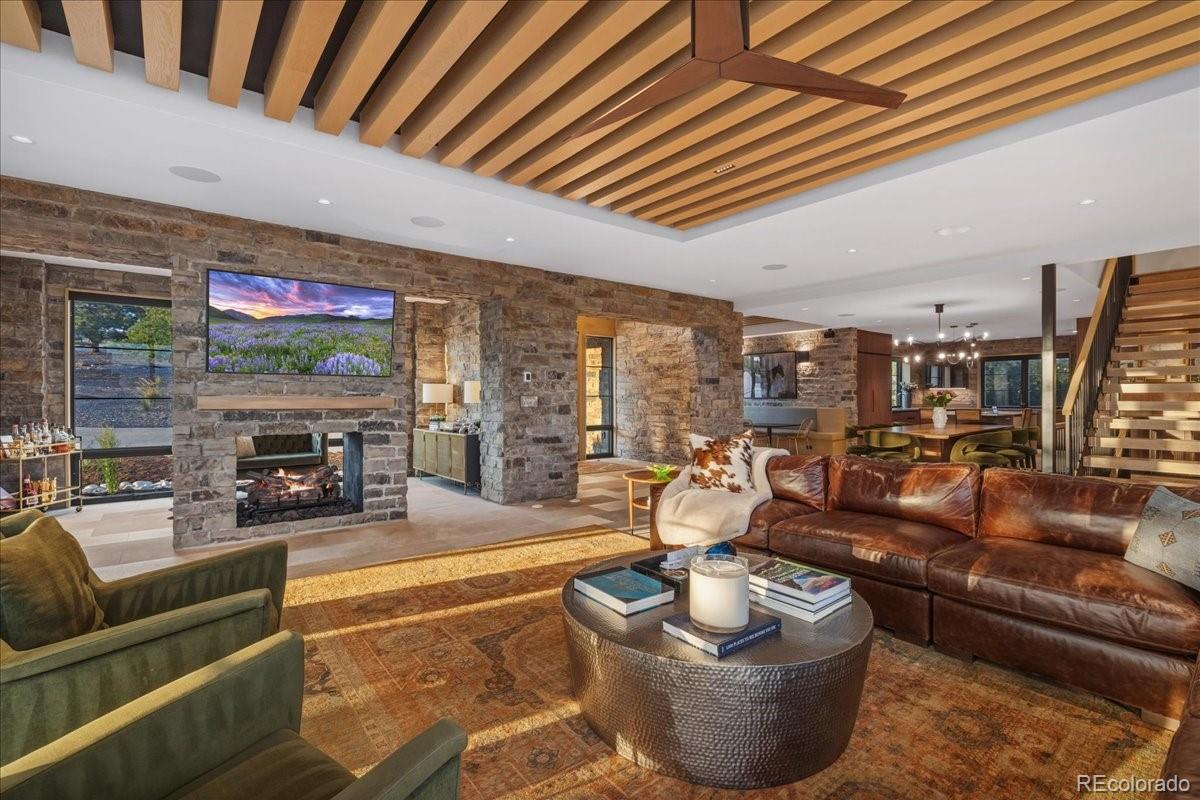 Great room with stone fireplace, mounted TV, and sectional seating