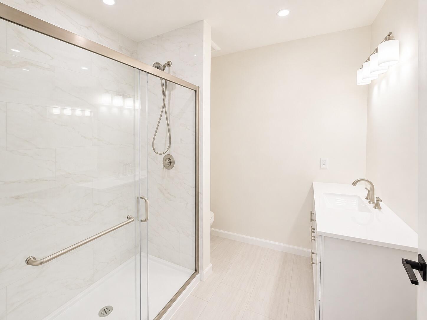 Bright bathroom with a marble-look tiled glass shower and a white vanity.