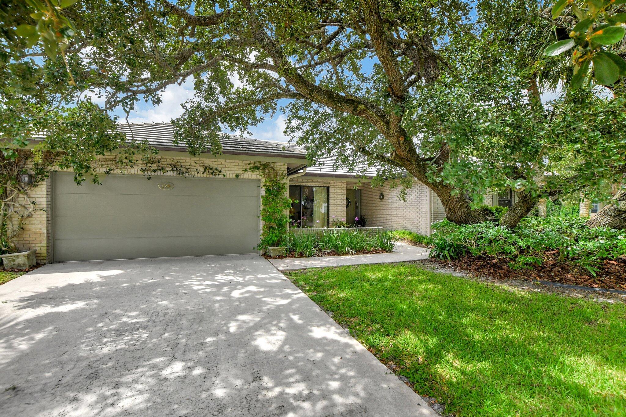 Brick home with a wide garage, shaded by a large oak tree over the front yard and driveway.