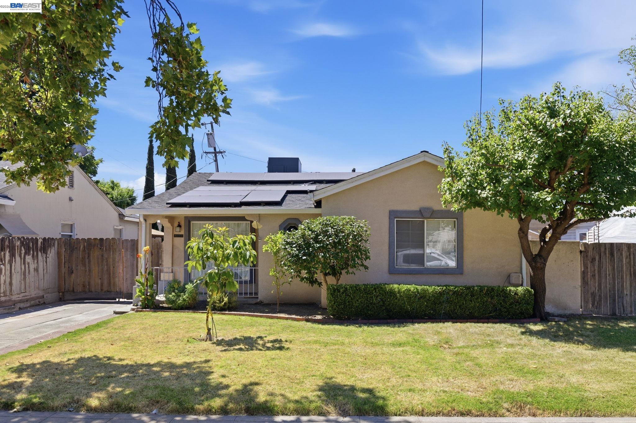 Home at 1330 W Park St with rooftop solar panels, a front lawn, and mature trees.