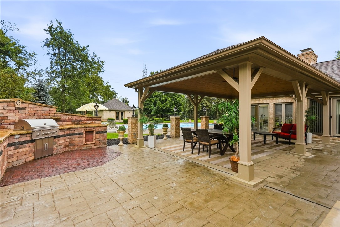 Covered backyard patio with dining area, built-in grill, and swimming pool.