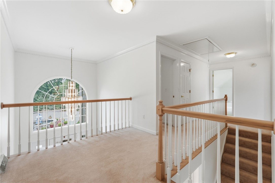 Carpeted upstairs landing with a staircase and a large arched window overlooking the front yard.