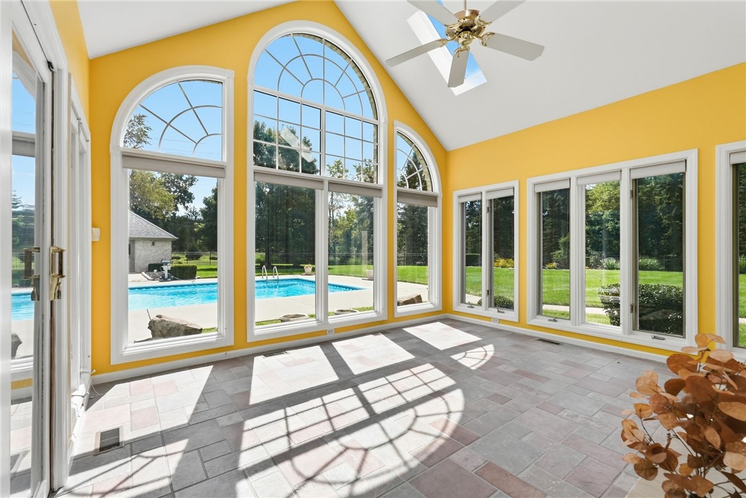 Sunroom with vaulted ceiling and arched windows overlooking a swimming pool.