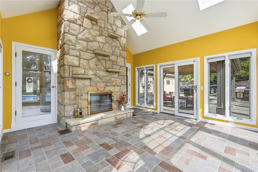 Sunroom with a floor-to-ceiling stone fireplace, patterned tile floor, and glass doors opening to a patio.