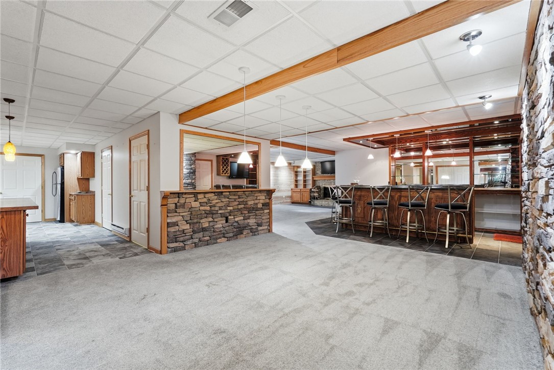 Finished basement with a long built-in bar, stone counter, and row of bar stools.