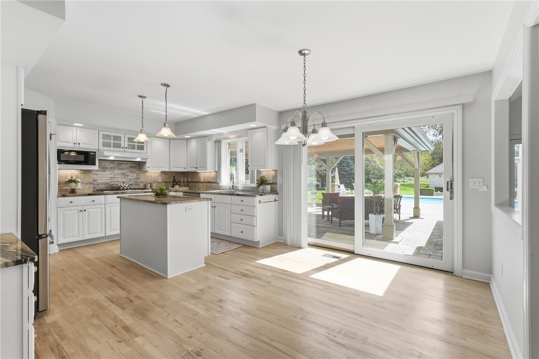 Bright white kitchen with a central island and sliding doors opening onto a patio and pool.