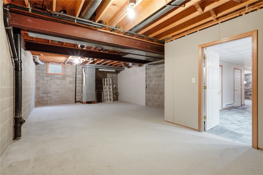 Unfinished basement with exposed ceiling joists and an open doorway to a tiled room.