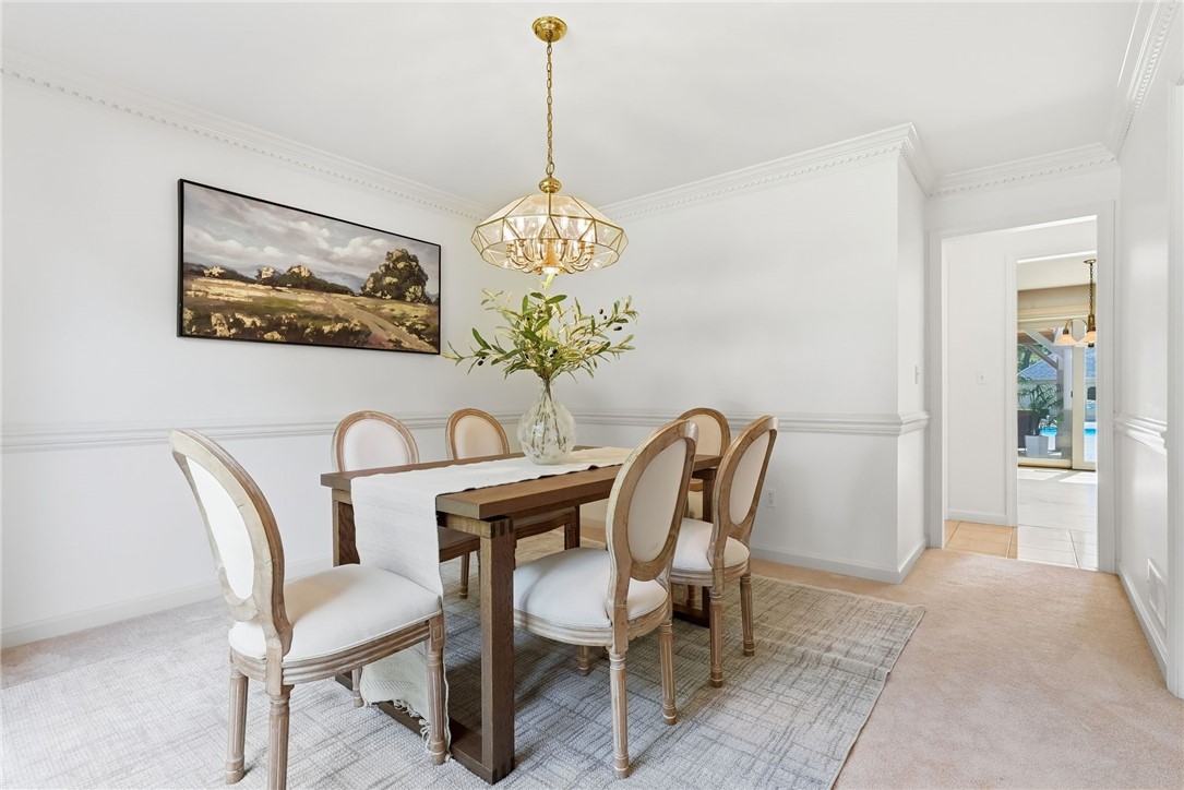 Furnished dining room with a dark wood table, brass chandelier, and white wainscoting.