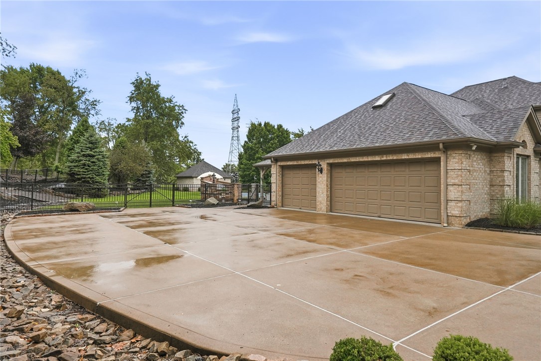 Brick garage with two brown doors and a broad concrete driveway bordered by landscaping.