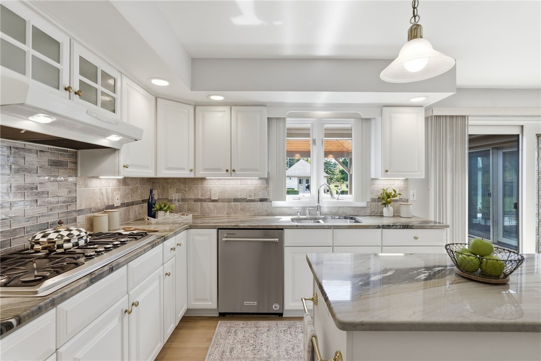 Bright white kitchen with a gray stone island and window over the sink.