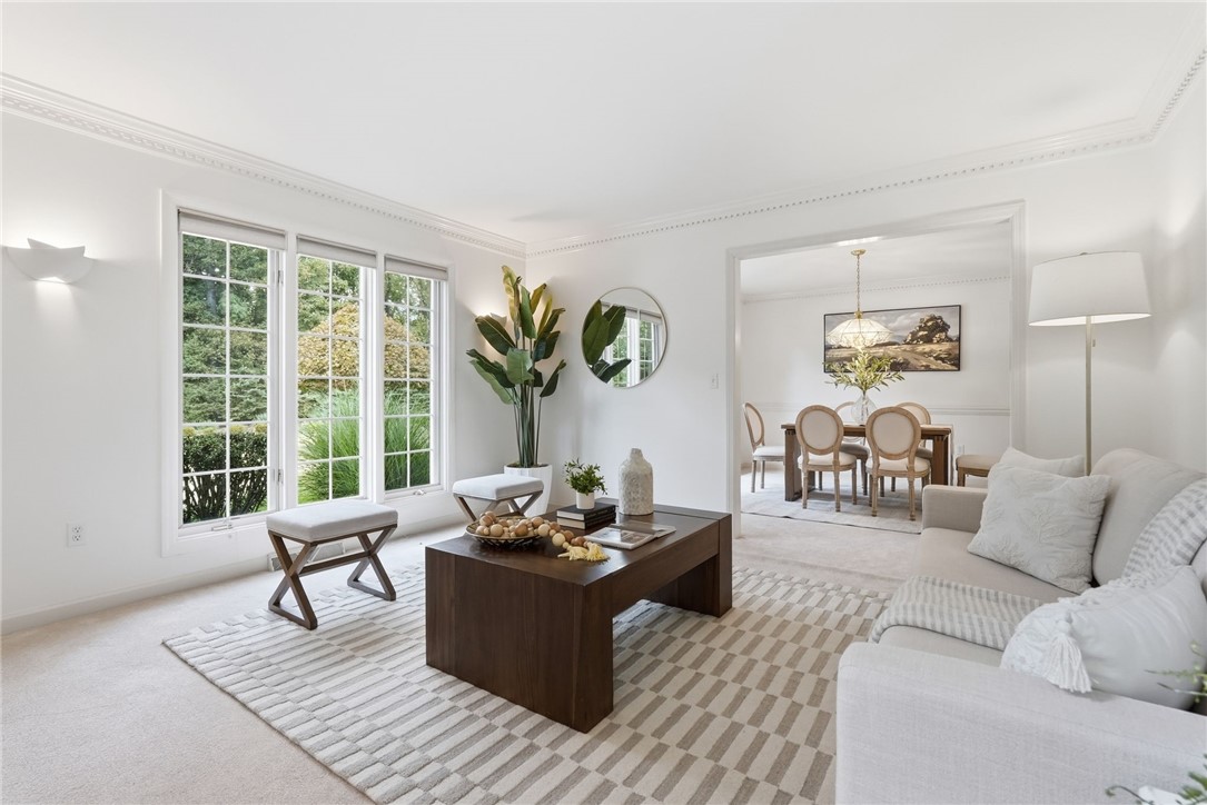 Bright living room with tall windows, a white sofa, and an adjoining dining room.