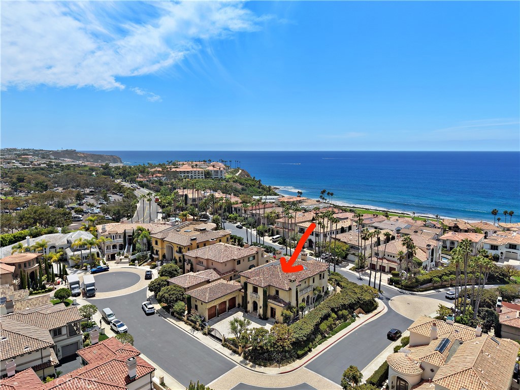 Coastal home marked by a red arrow, with the ocean and neighboring homes beyond it.