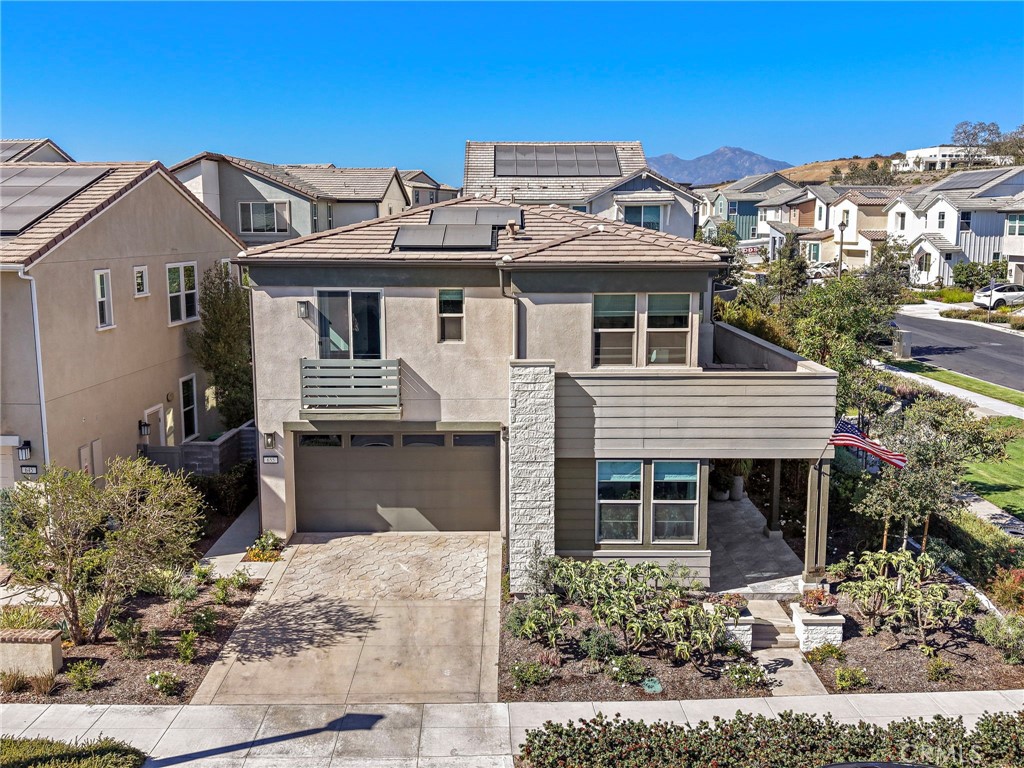 Two-story home with rooftop solar panels, a double garage, and an American flag by the entry.