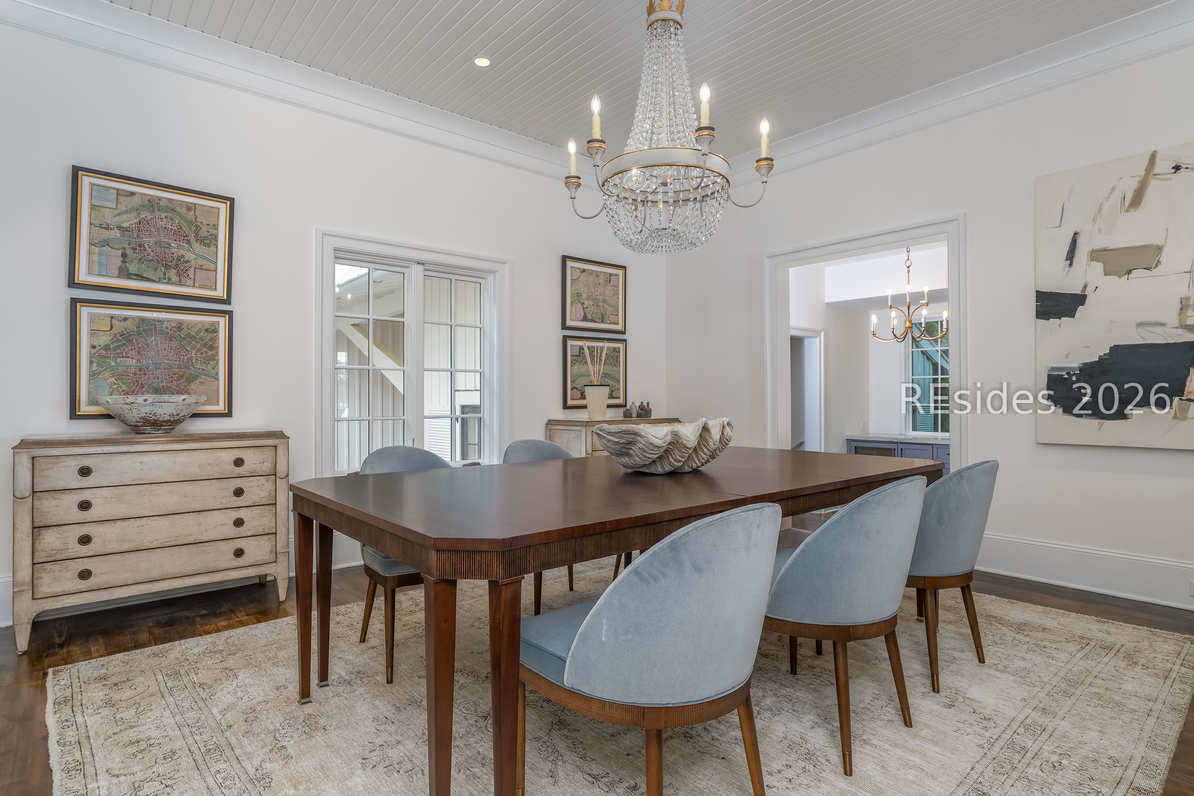 Dining room with a dark wood table, pale blue chairs, and a large crystal chandelier.