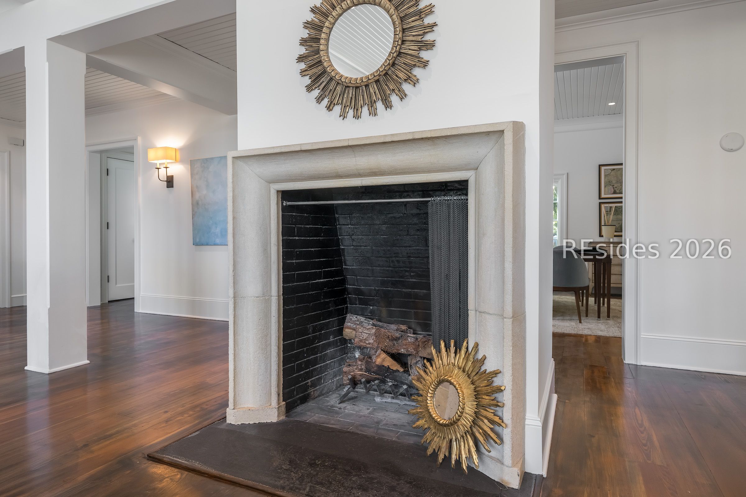 Stone-mantel fireplace with black brick firebox and decorative sunburst mirrors in a bright home interior.