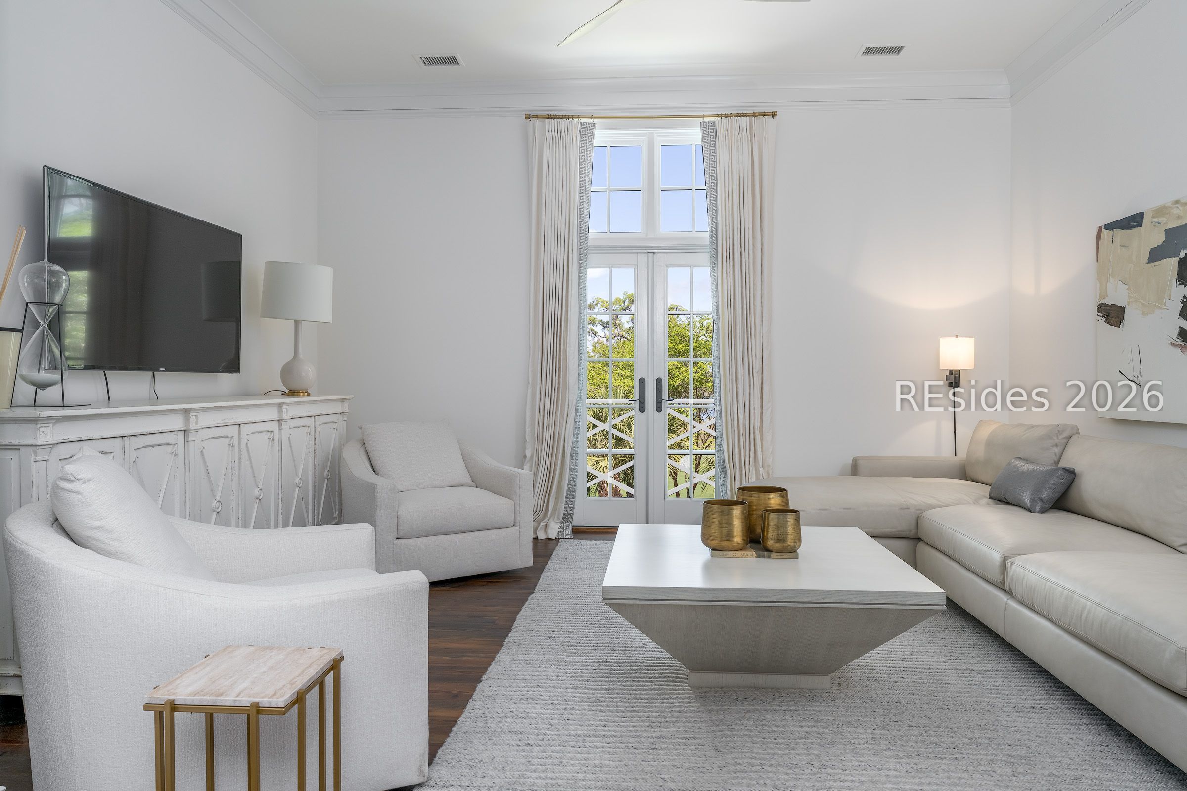 Furnished living room with a white sectional, armchairs, and tall French doors.