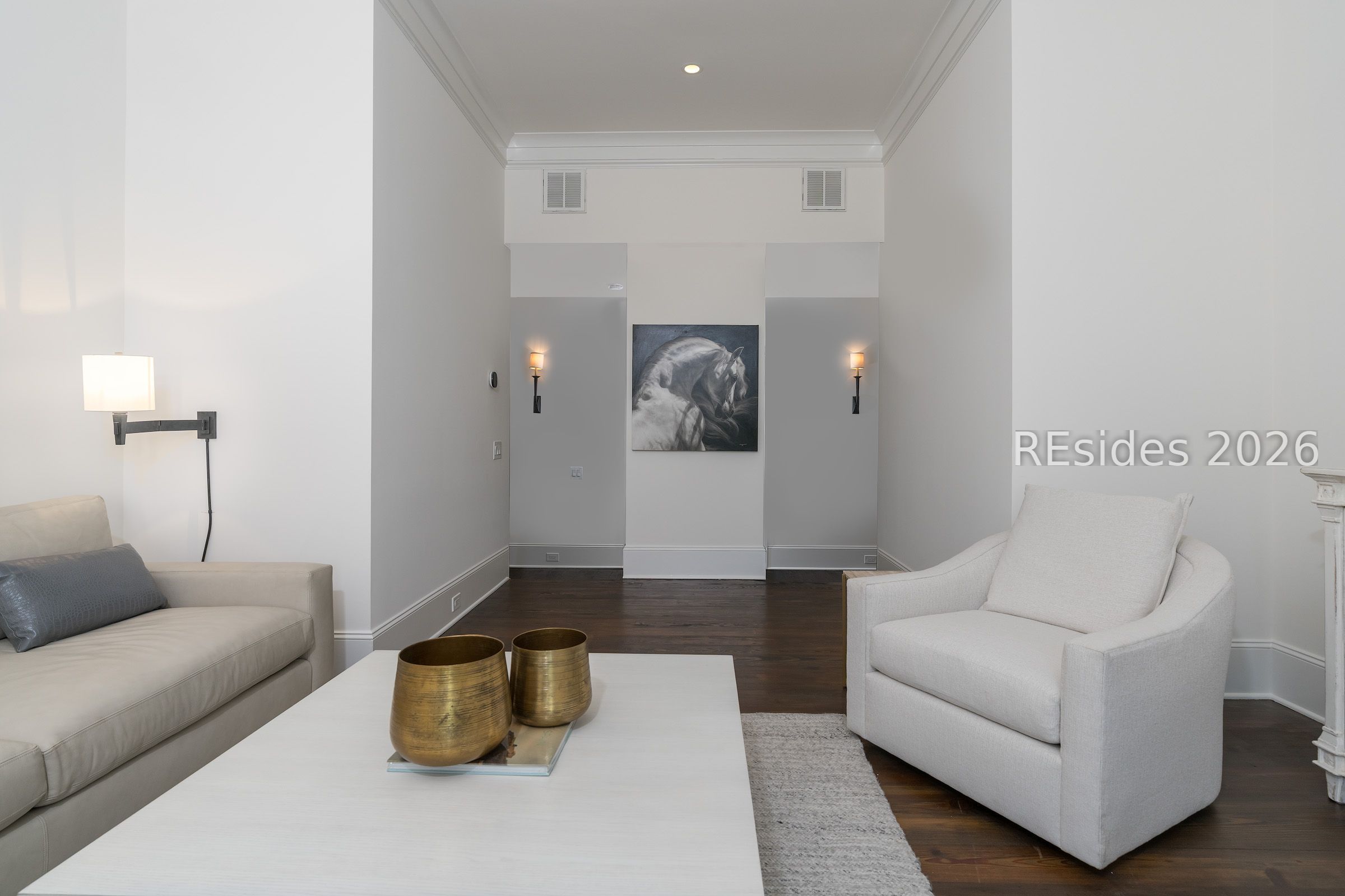 Furnished living room with white seating, dark wood floors, and horse artwork above the rear wall.