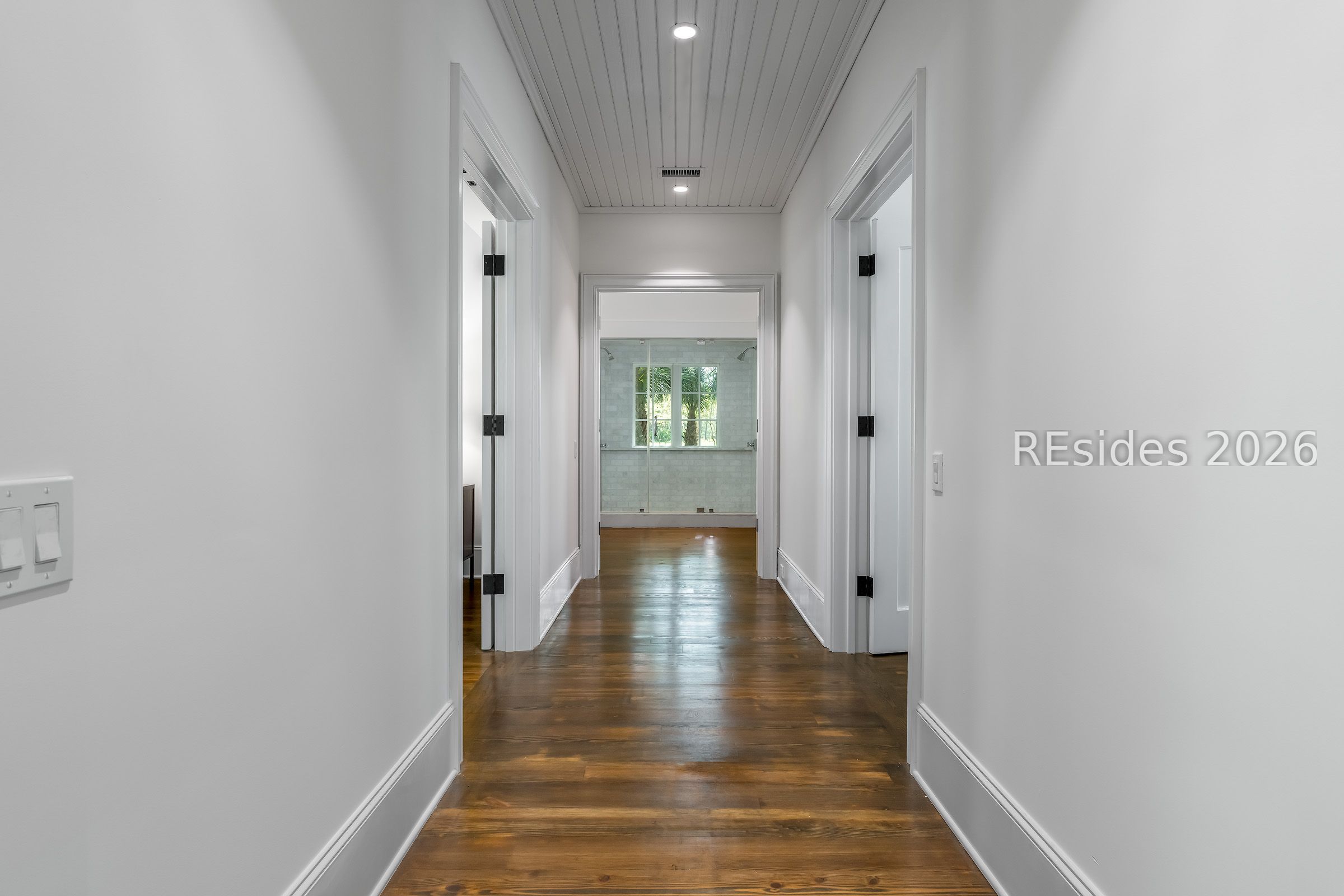 Bright hallway with dark hardwood floors and a tiled shower room visible at the far end.