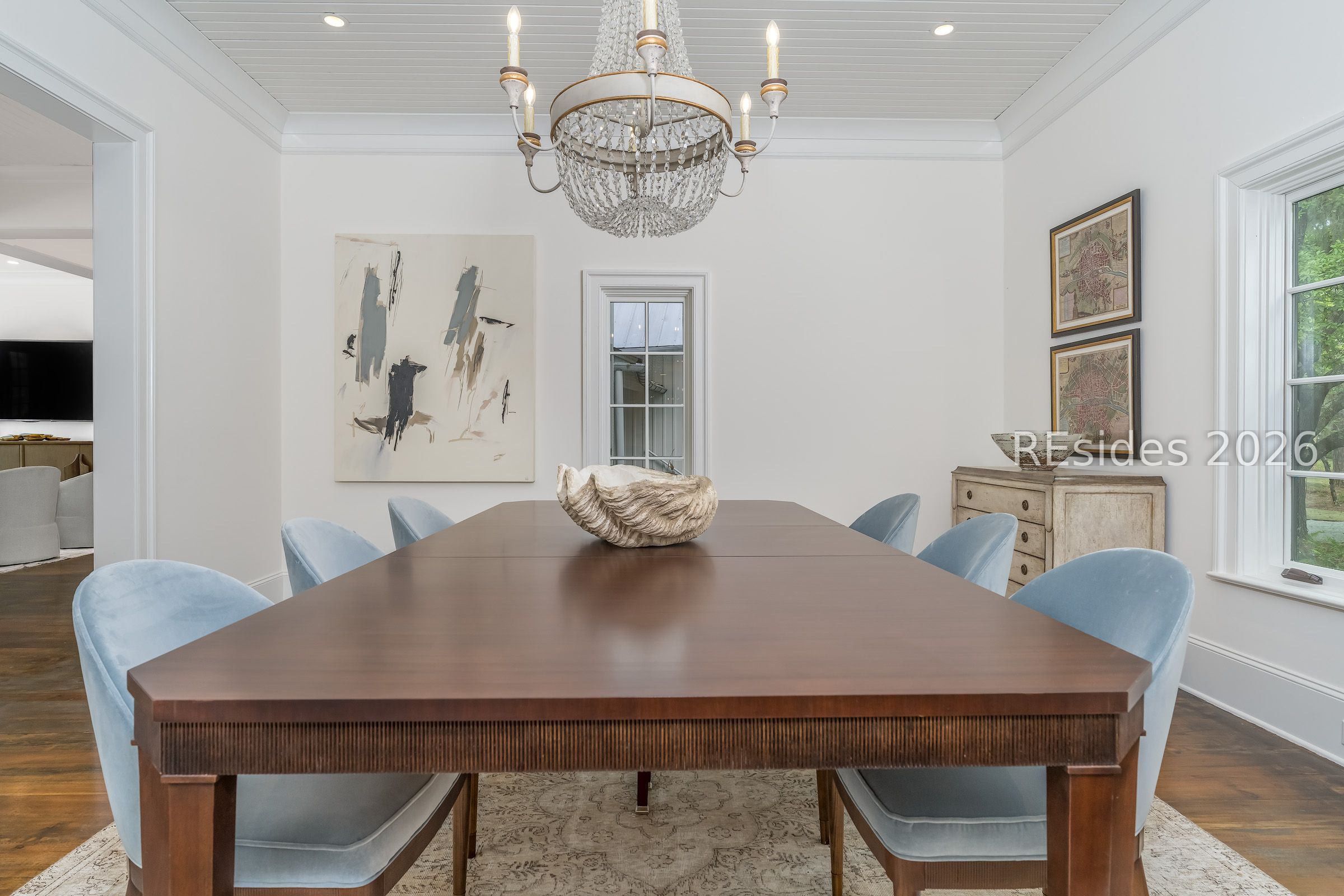 Dining room with a dark wood table, pale blue chairs, and a crystal chandelier.