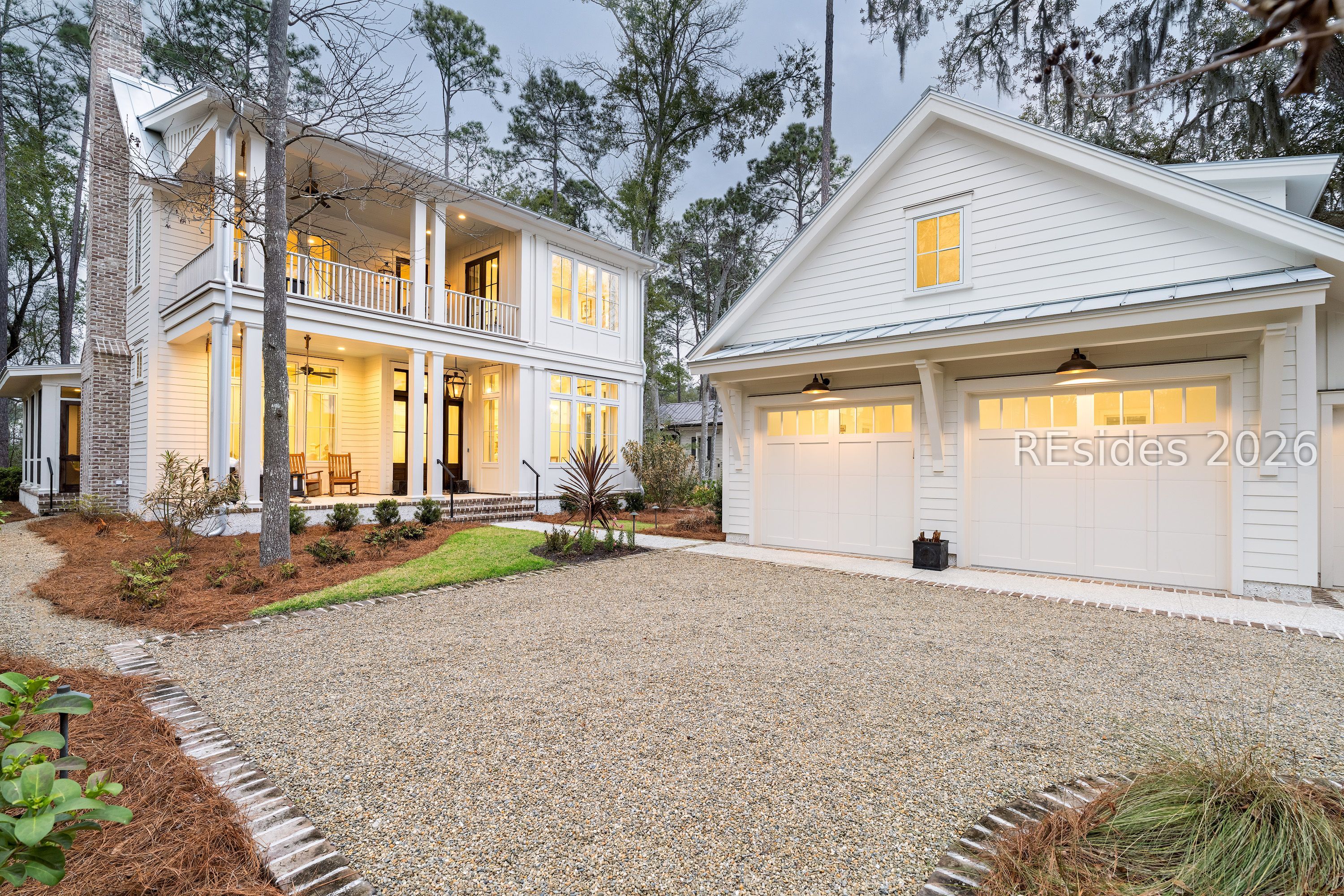 White two-story home with a covered porch, brick chimney, and attached double garage.