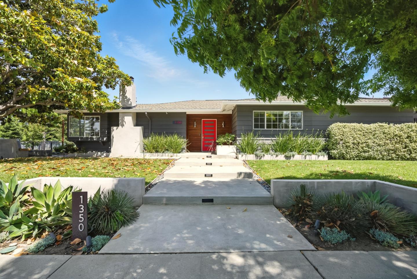 Single-story gray home with a red front door, white chimney, and landscaped walkway.