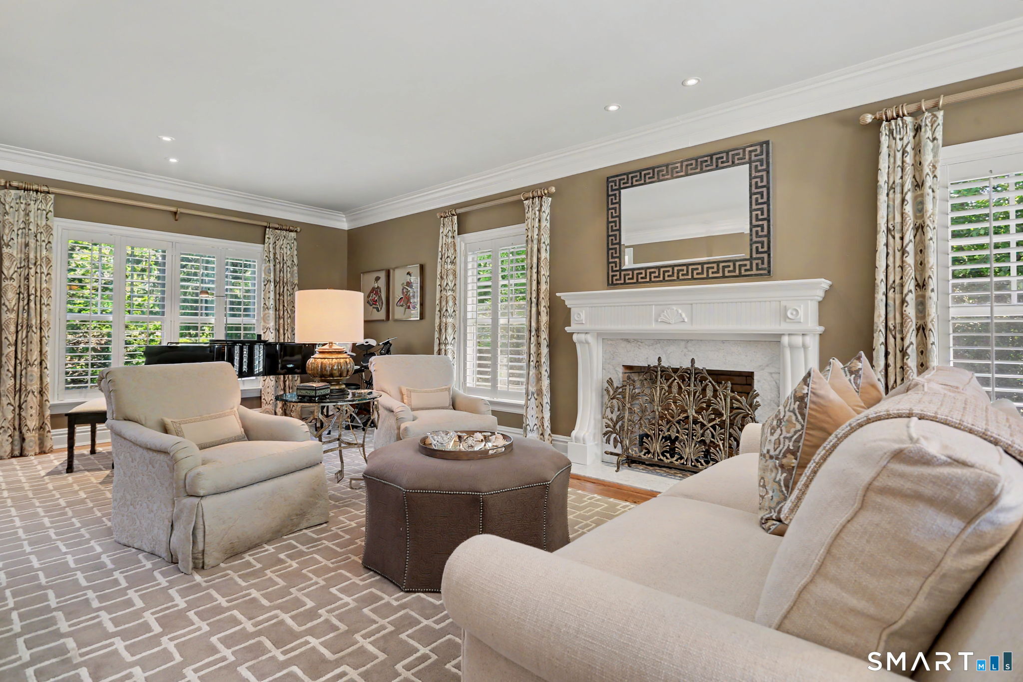 Living room with a white fireplace, cream seating, plantation shutters, and a black grand piano.