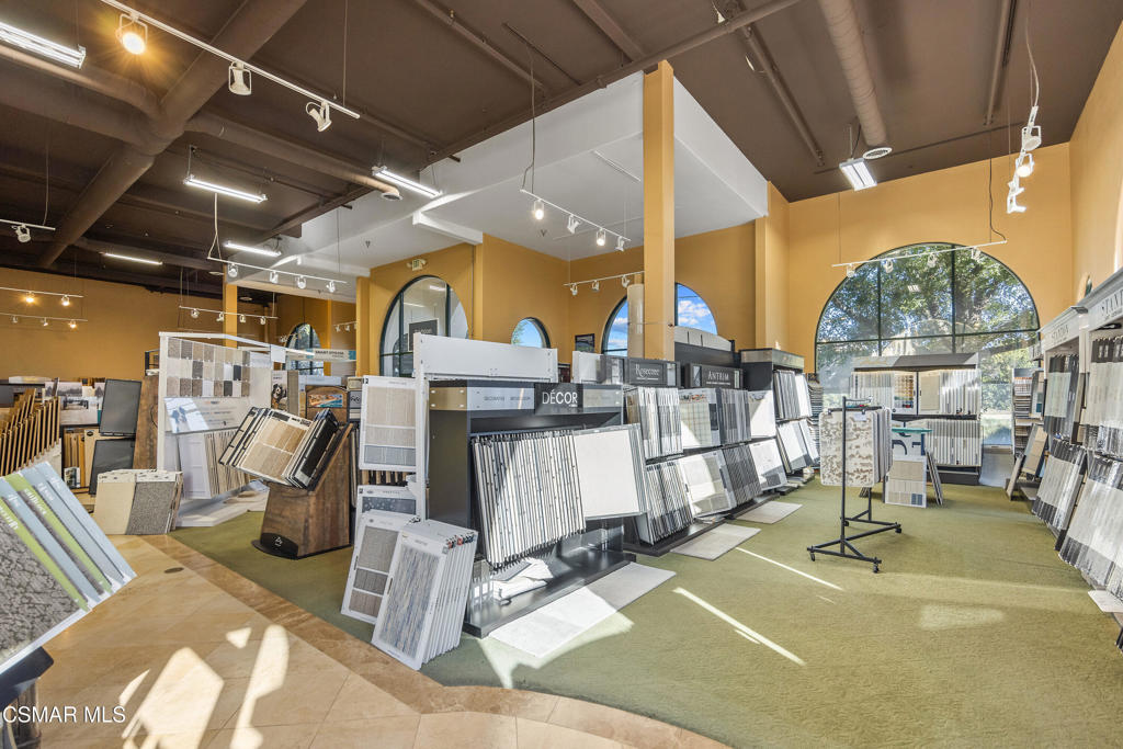 Flooring showroom interior with sample displays, mustard-yellow walls, and large arched windows.