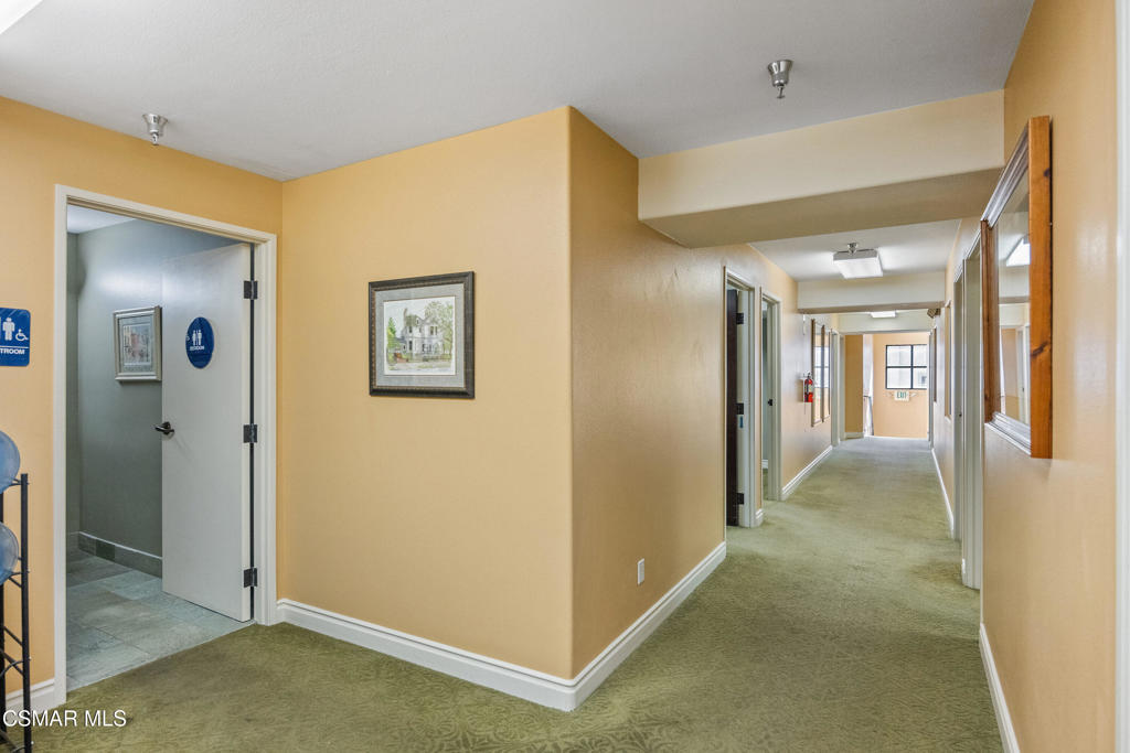 Interior hallway with green carpet, beige walls, and an open restroom door.