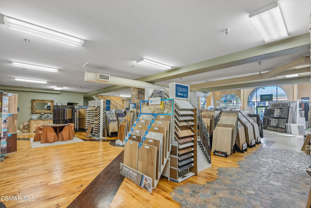 Flooring showroom with rows of sample displays, hardwood flooring, and arched front windows.