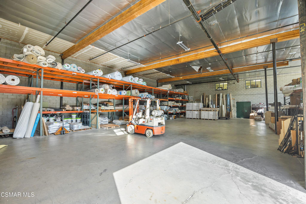 Warehouse interior with stocked industrial shelving and an orange forklift.