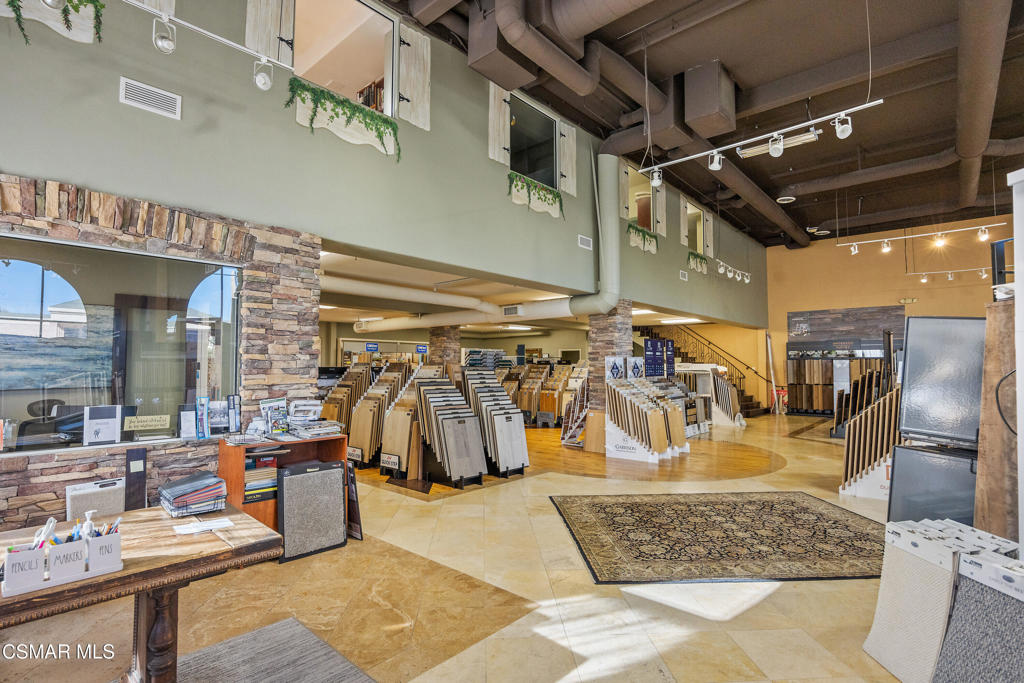 Flooring showroom with sample displays, a stone-clad counter, and exposed ceiling ductwork.