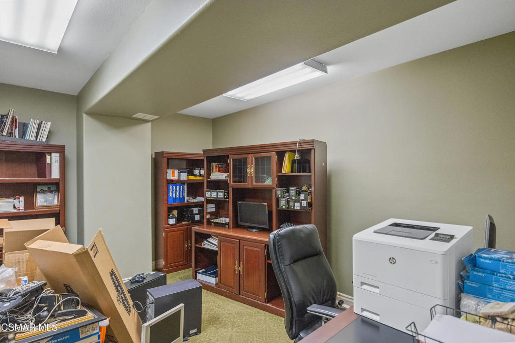 Office with dark wood cabinetry, a black chair, printer, and boxes and supplies.