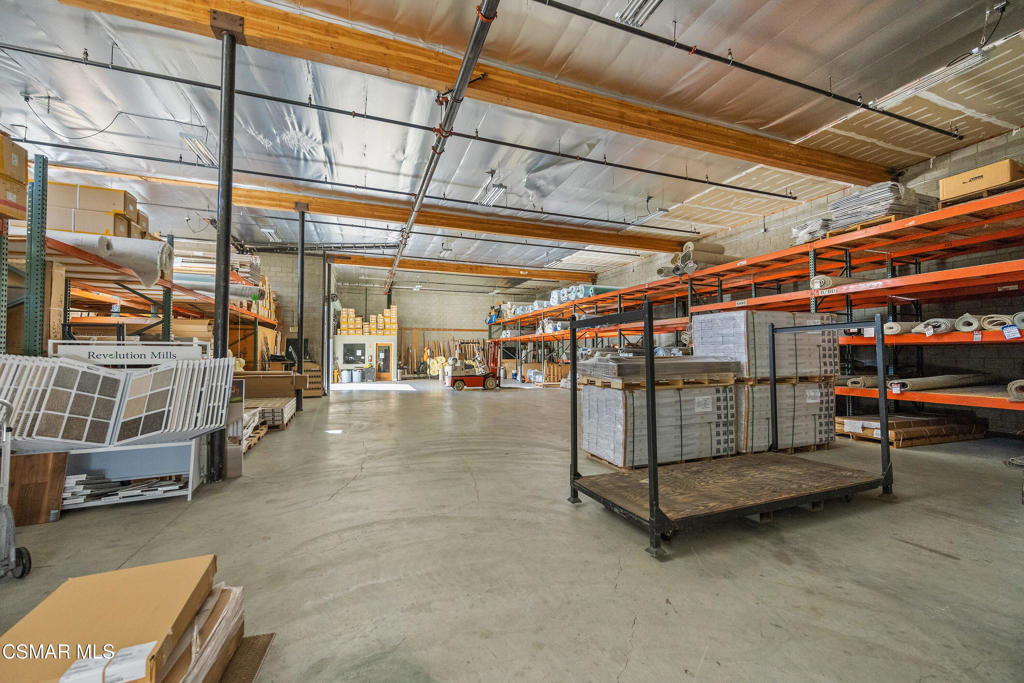 Commercial warehouse interior with industrial shelving and pallets of flooring materials.