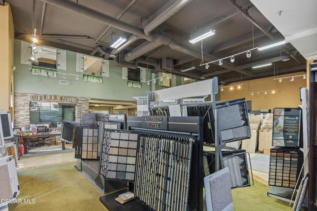 Commercial flooring showroom with rows of sample displays and exposed ceiling ducts.