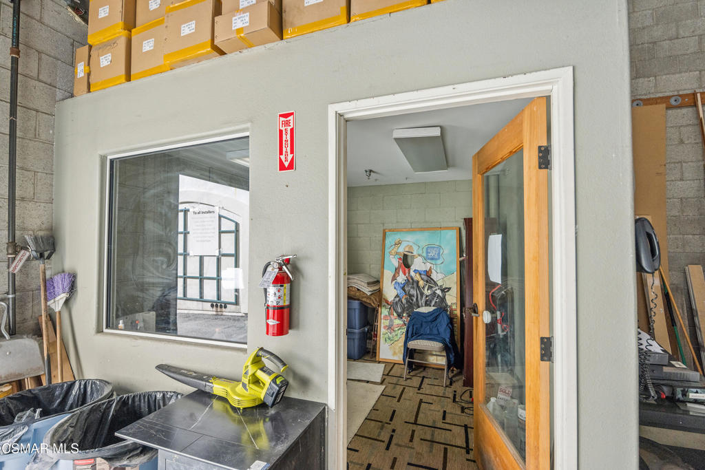 Workshop storage area with an open glass-panel door, high-shelf boxes, and a fire extinguisher.