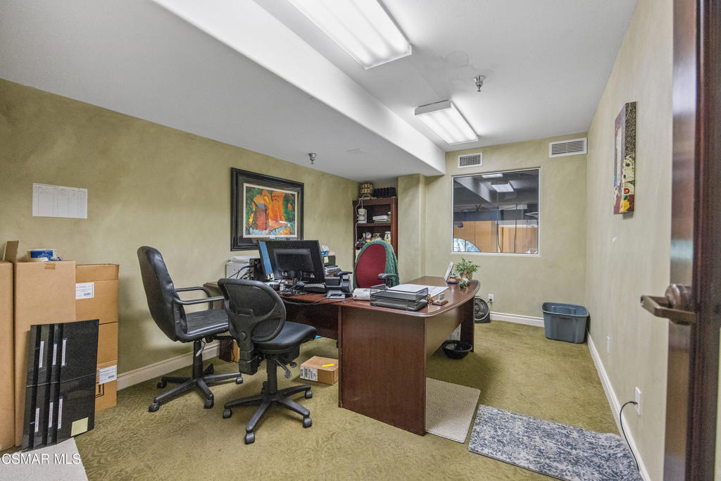 Office with a large wooden desk, several chairs, and green carpet.