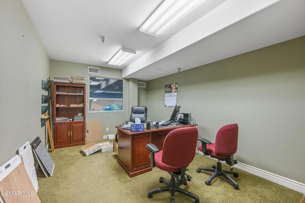Office with a wooden desk, two red chairs, computer, and built-in shelving.